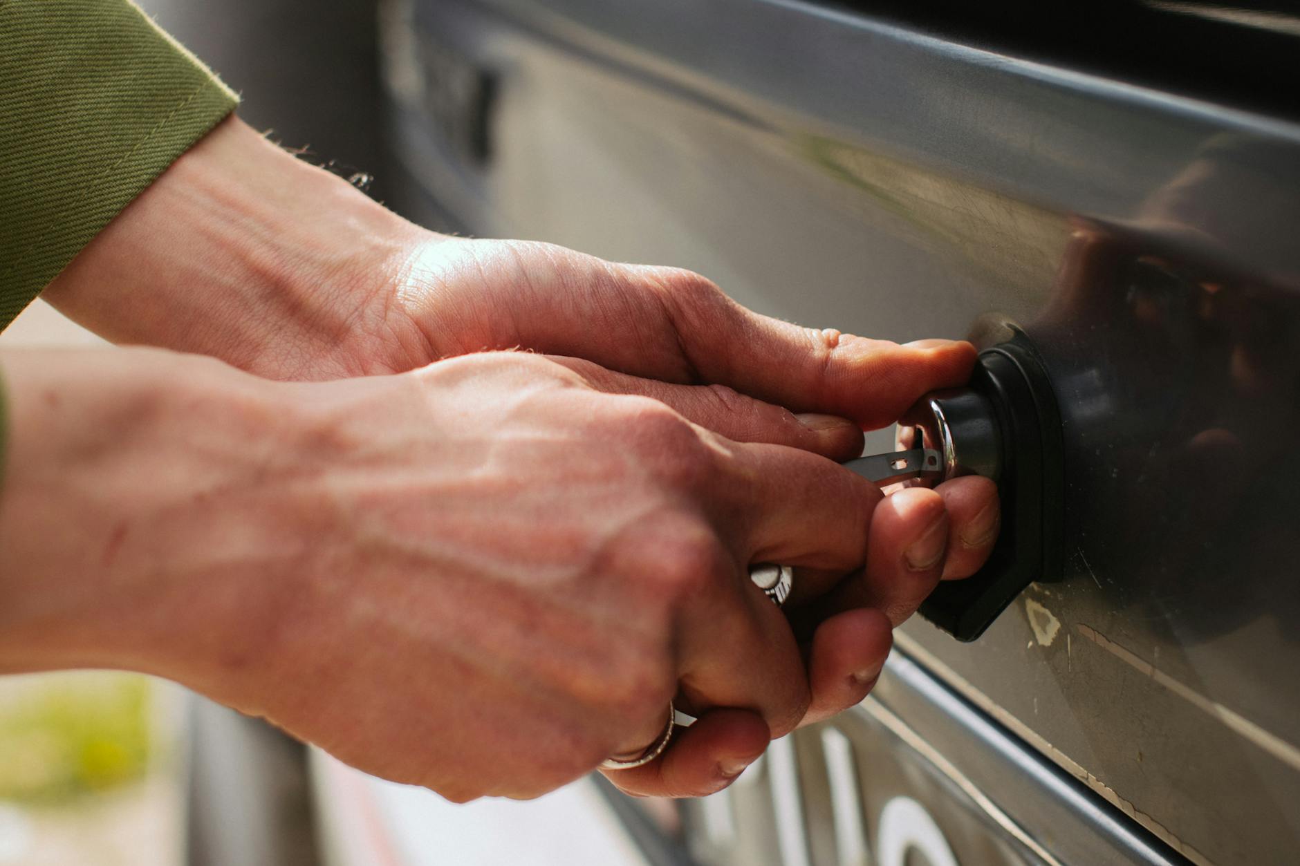 hands of a man unlocking car trunk with a key
